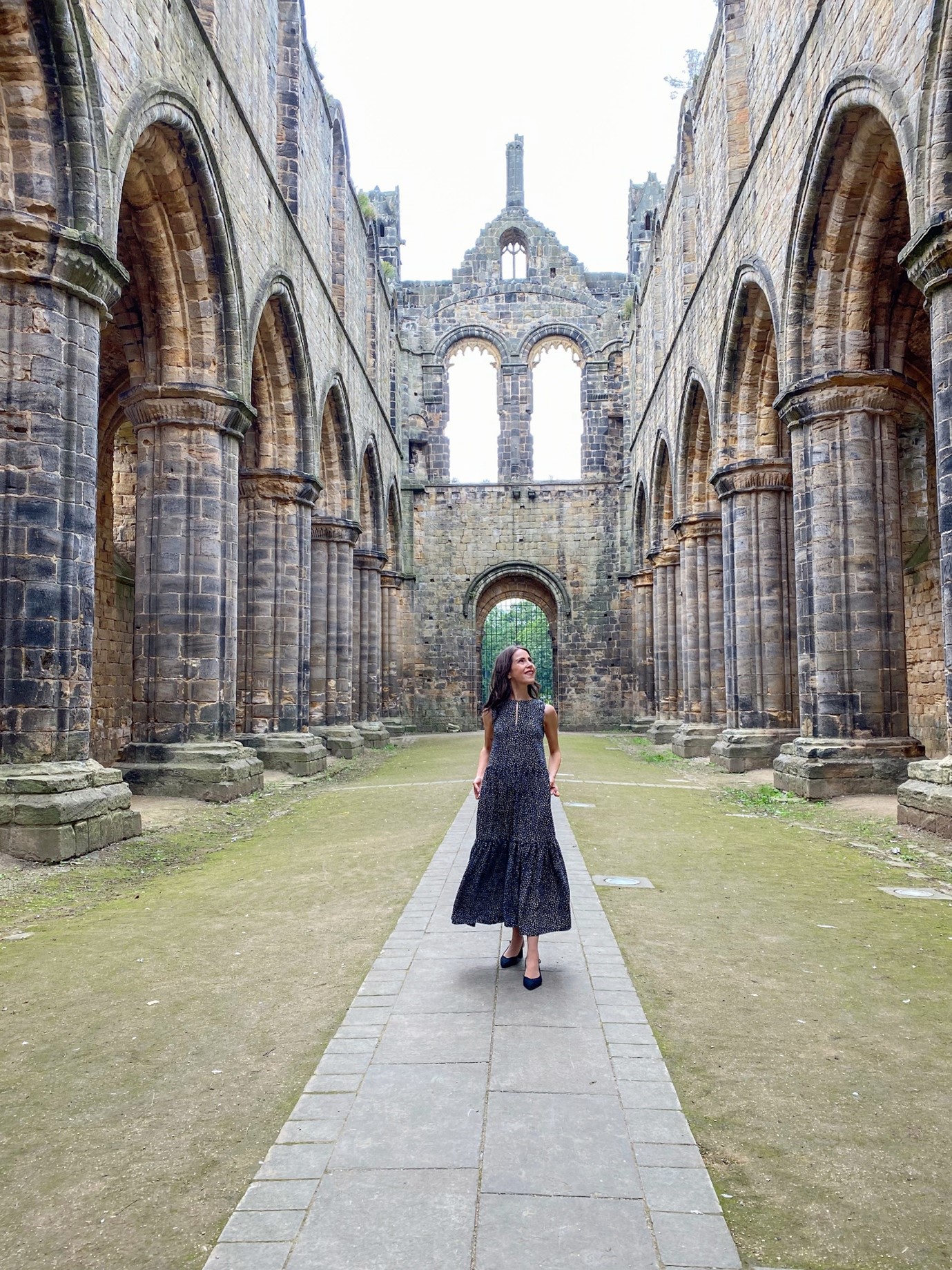 Woman stood among the ruins of Kirkstall Abbey
