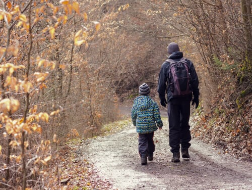 A child and parent walking through a wet forest.