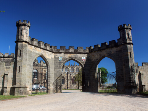 The front gate of Auckland Castle which is made up of three arches. There are two family emblems above the middle arch.