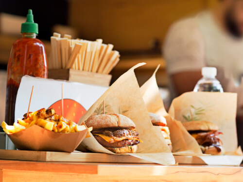 a tray of burgers and chips, there are condiments and cutlery options behind the food.