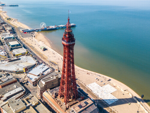 An aerial shot of Blackpool Tower with blue sea in the background on a sunny day