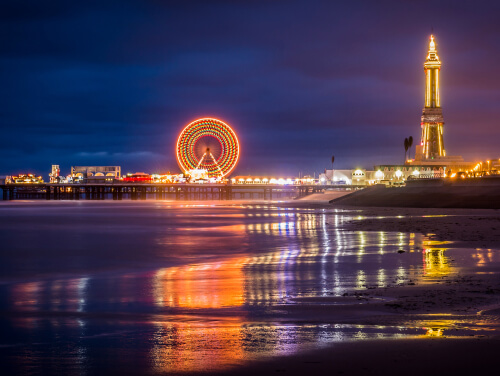 The Blackpool shoreline with the pier in the distance, lit up at night.