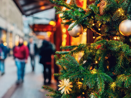 Close up of a decorated green Christmas tree with baubles and lights on it