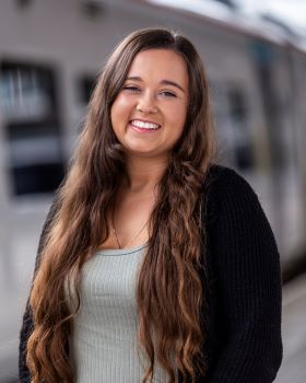 Image of Danielle Clarkson, smiling with long brown hair, black cardigan and grey t shirt