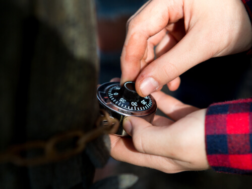 A person trying to figure out the code of a padlock.