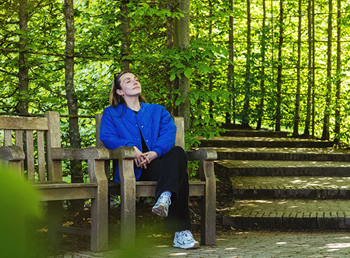 Woman in a blue jacket sitting on a wooden chair in the park