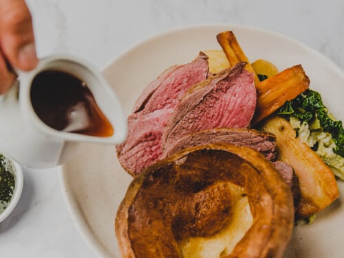 Plate of food including roast beef, vegetables and yorkshire pudding, with gravy