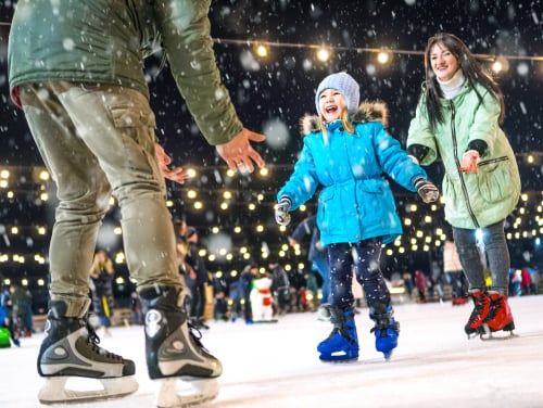 A child skating from their mother to their father, the father waits with open arms.