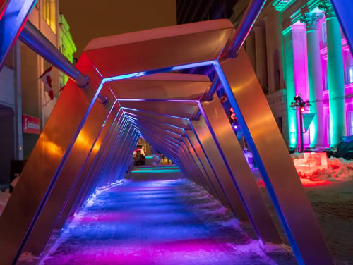 A tunnel made of metal arches with an array of lights lighting it up.