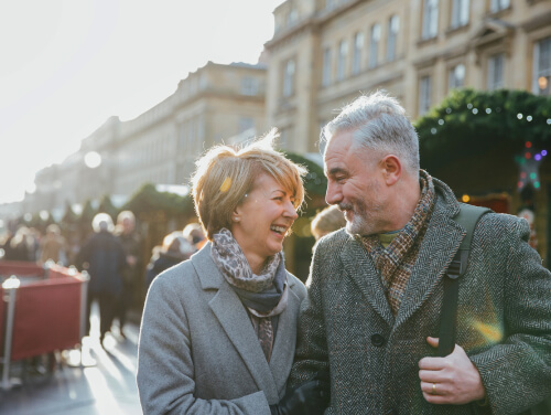 An elderly couple smiling at each other while at a Christmas market