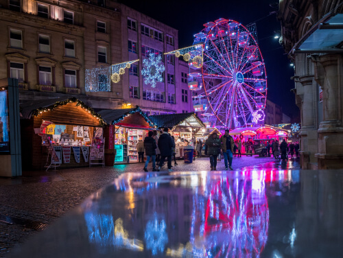 Sheffield Christmas market with stalls and a big wheel at night with lights