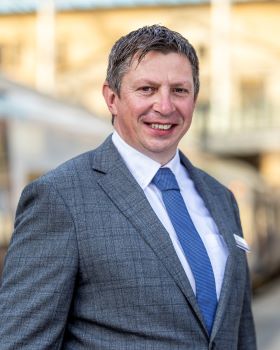 Professional image of Simon Abbott, wearing chequed suit and blue tie