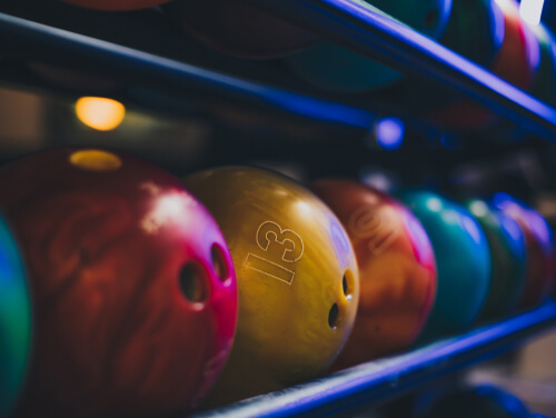 A rack of bowling balls of varying sizes waiting to be bowled.