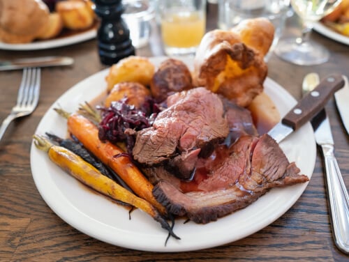 Plate of food including roast beef, vegetables and roasted carrots