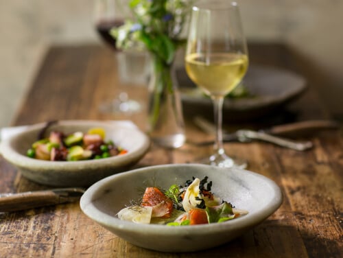 Plate of delicate looking food with a glass of white wine