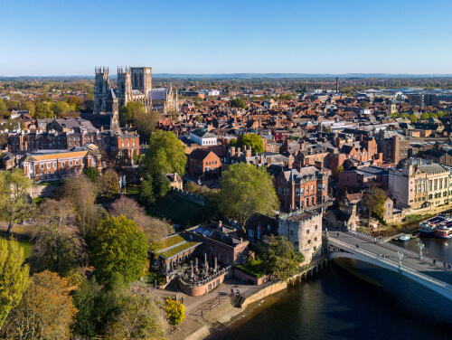 York city from above, with the cathedral in view and river busy with boats.