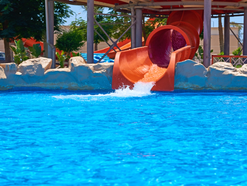 A water slide at a waterpark that is currently on, it feeds into a pool.