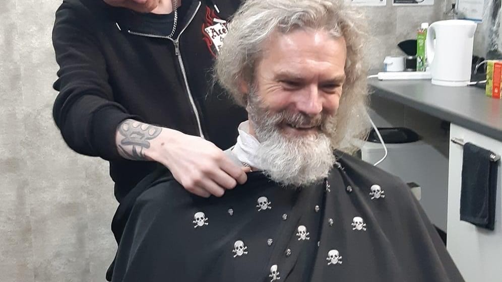 Danny sits in a barbers chair as his beard is cut